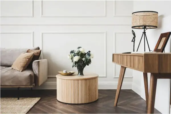Elegancki salon glamour z dominującym drewnem. Miękka sofa, okrągły stolik i biurko tworzą przytulną przestrzeń.