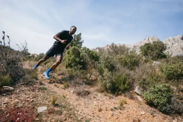 Un coureur en pleine action sur un sentier rocailleux, profitant d'une course à étapes dans un paysage aride et montagneux.