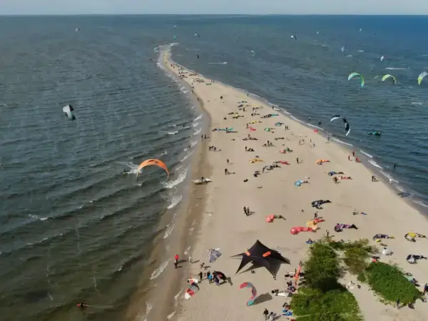 Rewa atrakcje dla dzieci: plaża pełna kolorowych latawców do kitesurfingu i ludzi odpoczywających na piasku.