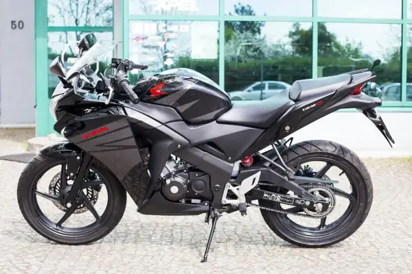 Czarny motocykl Honda CBR 125R z automatyczną skrzynią biegów, gotowy do jazdy po mieście.