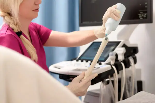 Lekarka przygotowuje sondę USG do badania, aplikując żel. Badanie pozwala ocenić stan endometrium po menopauzie.
