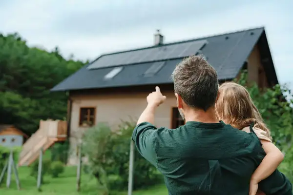Padre e figlia guardano il tetto con pannelli solari. Un impianto fotovoltaico da 5 kW può produrre molta energia al giorno.