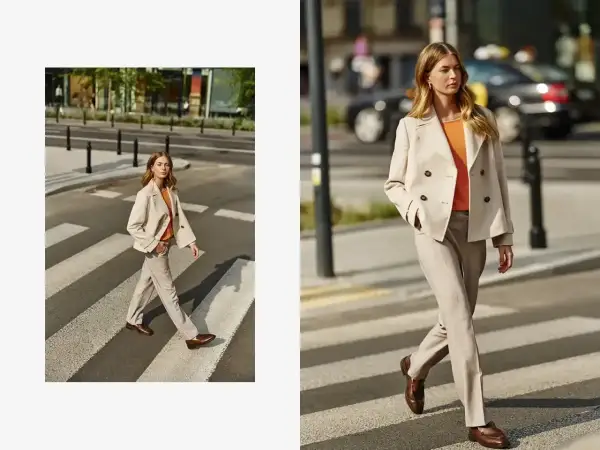Elegancka beżowa marynarka damska w połączeniu z jasnymi spodniami i pomarańczową bluzką tworzy stylowy miejski look.