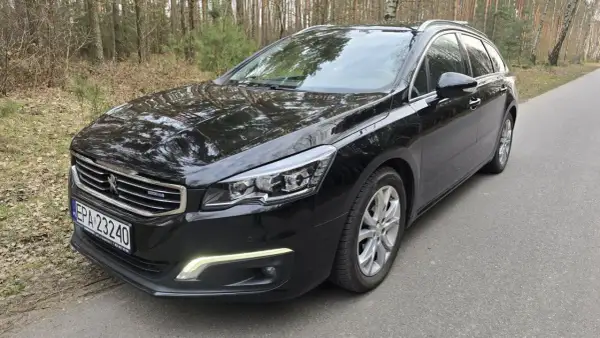 Czarny Peugeot 508 kombi z silnikiem 2.0 HDI 150KM na leśnej drodze.