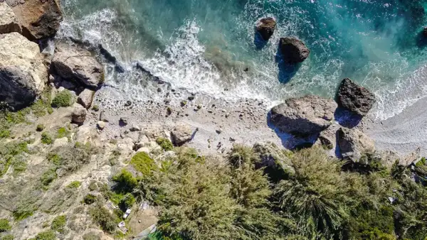 Vista aérea de la cala Barranco de Maro, con rocas, vegetación y el mar turquesa.