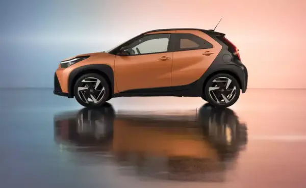 Pomarańczowy samochód miejski z czarnymi elementami, odbijający się w błyszczącej podłodze. Idealny do miasta!
