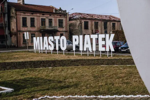 Napis "Miasto Piątek" na tle starych kamienic. To środek Polski, gdzie każdy dzień może być jak piątek.