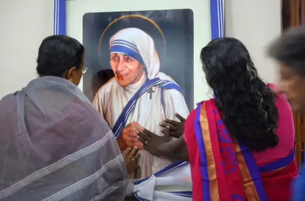 Frauen berühren ein Bild von Mutter Teresa, die ihr Leben den Armen widmete.
