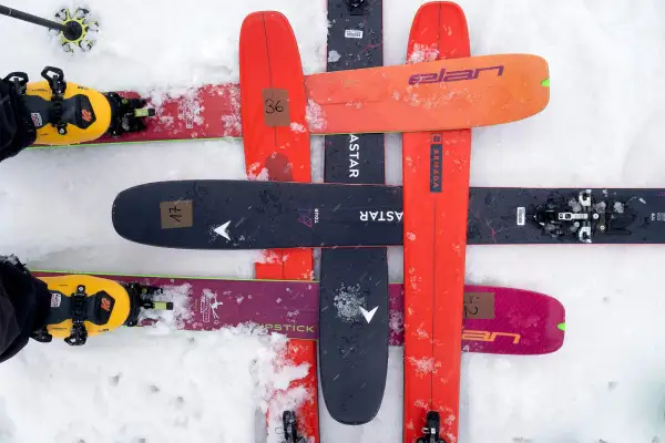 Skier mit gelben Tourenschuhen und Skiern in verschiedenen Farben, darunter ein schwarzer Ski mit der Aufschrift "black crows navis freebird".