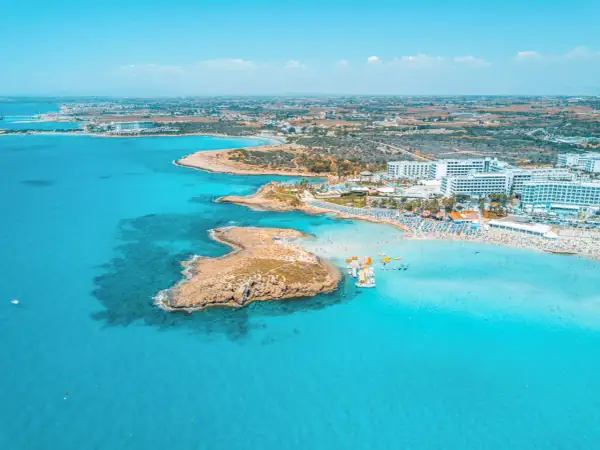 En livlig strand med turkost vatten, solbadande och vattensporter. Perfekt för Ayia Napa aktiviteter.