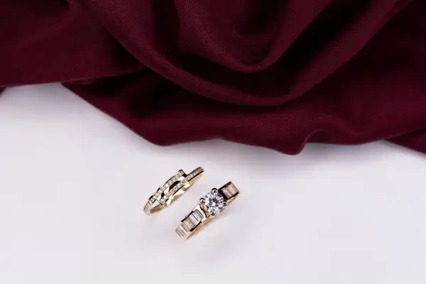 Dos anillos de oro, uno de compromiso con diamante y otro de alianza con diamantes pequeños, listos para combinar.