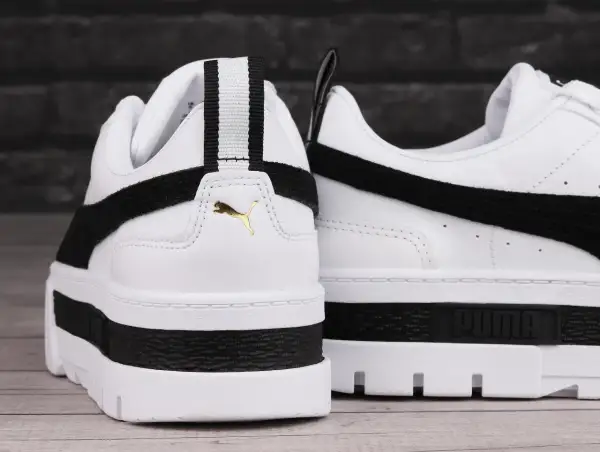 Białe buty sportowe Puma Mayze Leather z czarnymi akcentami i złotym logo. Gruba podeszwa dodaje im charakteru.