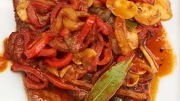 Ein saftiges Paprikaschnitzel-Rezept mit geschmortem Paprika, Zwiebeln und Pilzen, garniert mit einem Lorbeerblatt.