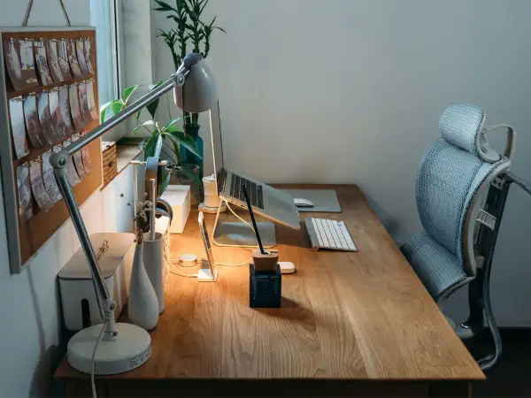 Bureau en bois avec plan de travail, ordinateur portable, lampe, clavier et chaise ergonomique. Une idée d'espace de travail fonctionnel et esthétique.