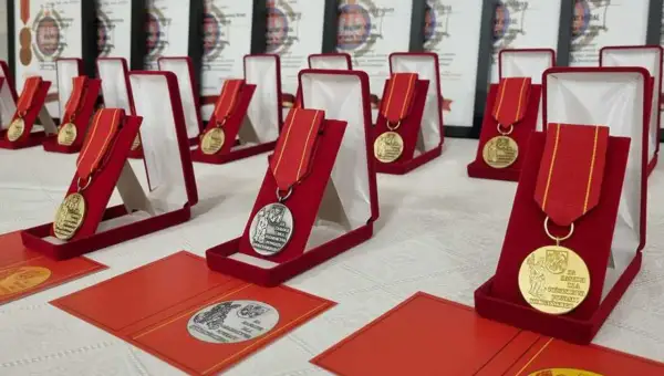Medale za zasługi dla pożarnictwa w czerwonych etui, gotowe do wręczenia. W tle dokumenty potwierdzające odznaczenia.