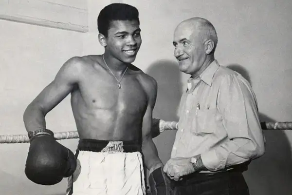 En ung Muhammad Ali ler mot sin tränare i ringen.
