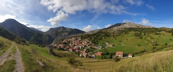 Pueblo de Sotres en los Picos de Europa, ideal para explorar sus rutas. Casas de piedra y tejados rojos entre verdes prados y montañas.