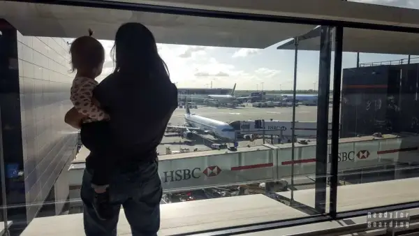 Mama z dzieckiem na rękach patrzy na samoloty. Czas na boarding, przygoda czeka!