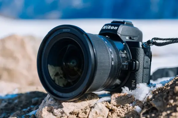 Nikon Z 50, jeden z popularnych bezlusterkowców, leży na kamieniach w zimowej scenerii.