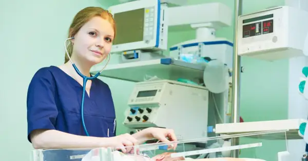 Młody neonatolog zafascynowany pracą przy inkubatorze, otoczony aparaturą medyczną.
