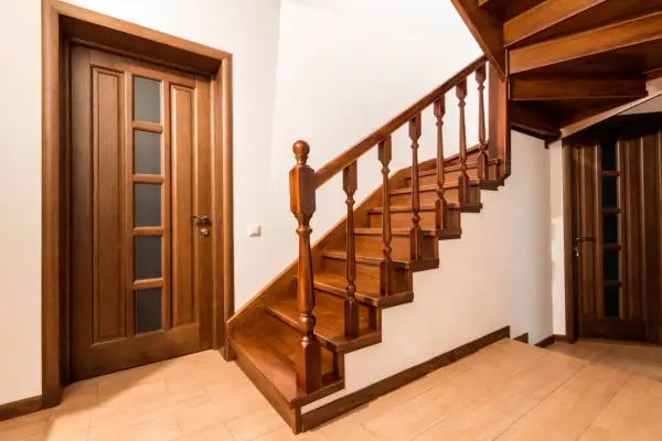 Una pittura di scale in legno scuro, con una porta in legno a sinistra e un'altra porta in legno a destra.