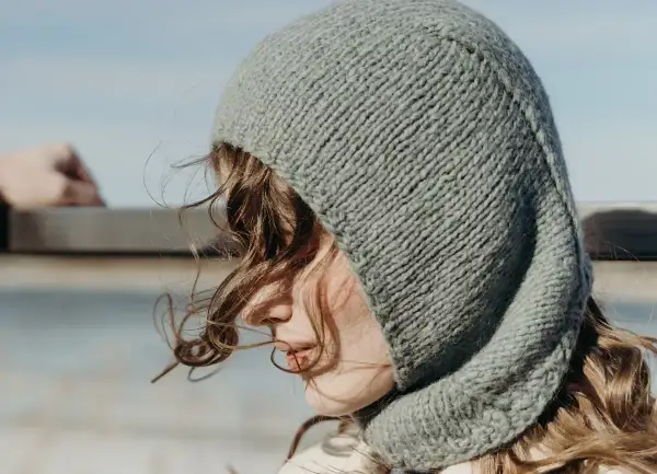 Una joven con un gorro tejido gris, que recuerda al balaclava origen, mira al horizonte.