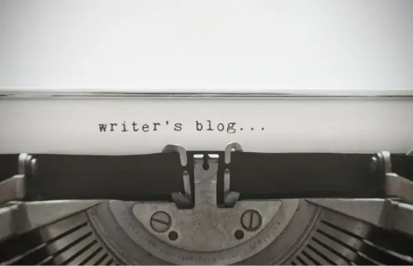 Maszyna do pisania z napisem "writer's blog...". Zastanawiasz się, jak napisać bloga po angielsku? Zacznij od tego!