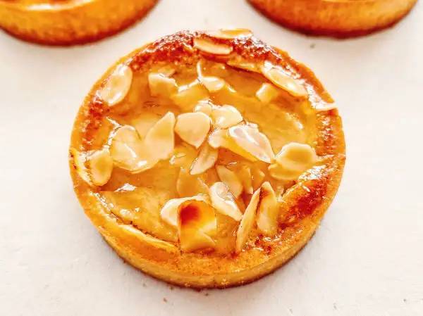 Tarte poire amandine dorée, garnie d'amandes effilées et d'un glaçage brillant. Un délice croustillant et fruité.