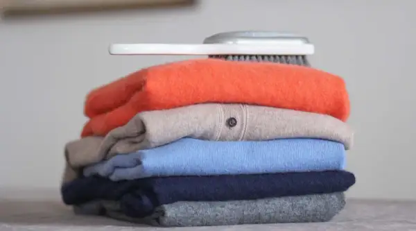 Ein Stapel bunter Kaschmirpullover, bereit für die Pflege. Was ist Kaschmir? Weiche Wolle für luxuriöse Kleidung.