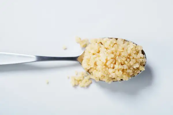 Ein Löffel voller gekochter Quinoa, bereit für eine gesunde Mahlzeit.