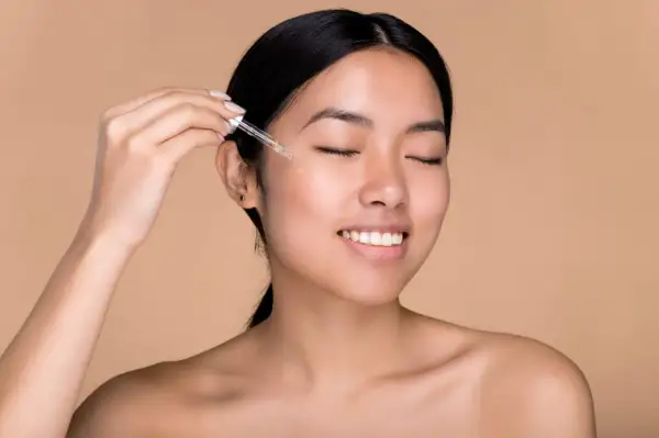 Donna applica acido ialuronico sul viso con un contagocce per una pelle idratata e luminosa.