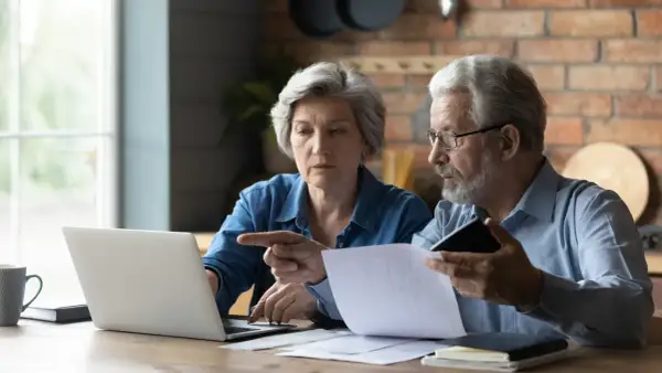 Para, mam 60 lat i 10 lat pracy, czy dostanę emeryturę? Zastanawiają się nad tym, analizując dokumenty i dane na laptopie.
