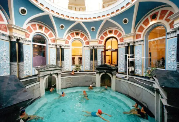 Wnętrze z basenem, gdzie ludzie relaksują się w gorącym źródle. Architektura z błękitnymi i pomarańczowymi zdobieniami.