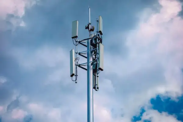 Wieża telekomunikacyjna z antenami, gotowa do obsługi sieci 5G, na tle burzowego nieba.