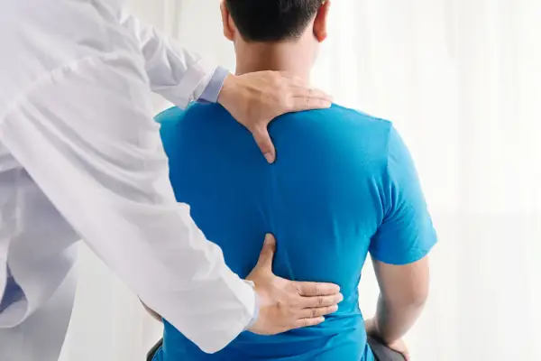 Un osteopata esamina la schiena di un paziente, aiutando a trovare sollievo dal mal di schiena.