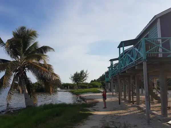 Kobieta na plaży, palmy i domki na palach. Idealne miejsce na belize wakacje.