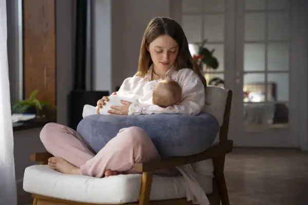 Młoda mama karmi piersią dziecko, skupiona na maluszku. Czy botoks a karmienie piersią to bezpieczne połączenie?