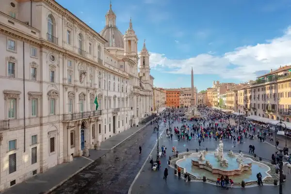 Una vivace piazza barocca a Roma, con la Fontana dei Quattro Fiumi al centro e la chiesa di Sant'Agnese in Agone sullo sfondo.