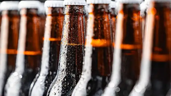 Bottiglie di birra ambrata, bagnate di condensa, perfette per chi cerca una birra piccola calorie.