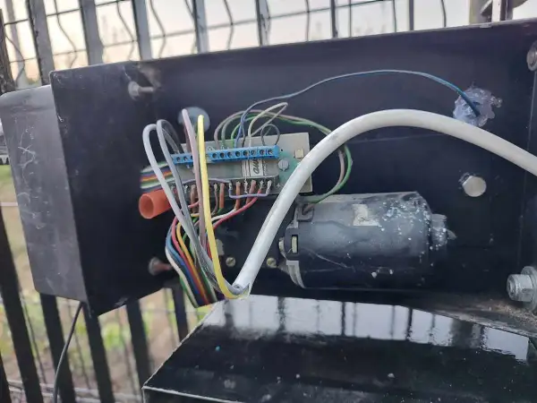 Mechanizm bramy: silnik, płytka drukowana i plątanina przewodów. Brama otwiera się ale nie zamyka, problem tkwi w tym skomplikowanym układzie.