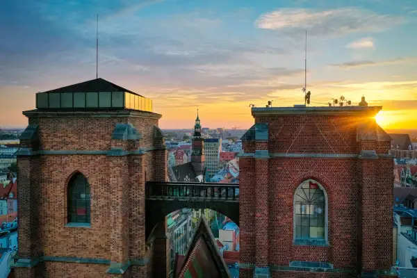 Zachód słońca nad Wrocławiem, widok na Most Czarownic między ceglanymi wieżami.