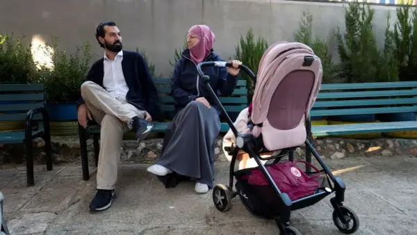 En man och en kvinna, som representerar muslimer i Sverige, sitter på en bänk med en barnvagn.