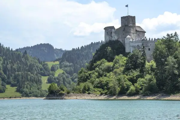 Zamek w Czorsztynie góruje nad jeziorem, otoczony zielonymi wzgórzami i lasami.