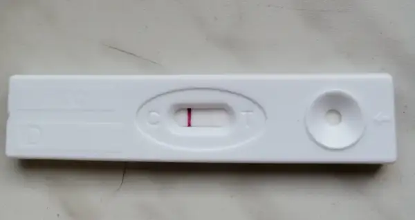 Blada kreska na teście ciążowym, widoczna przy literze "C", sugeruje wynik negatywny.