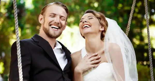 Coppia felice ride su un'altalena, perfetta per frasi per matrimonio e battesimo insieme.