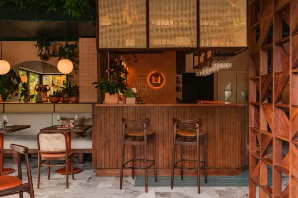 Przytulne bistro na piętrze z drewnianym barem, wygodnymi siedzeniami i mnóstwem zieleni.