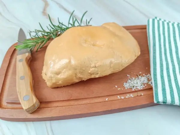 Un trozo de foie gras sobre tabla de madera, con romero, sal y un paño a rayas. La diferencia entre foie y foie gras es la preparación.
