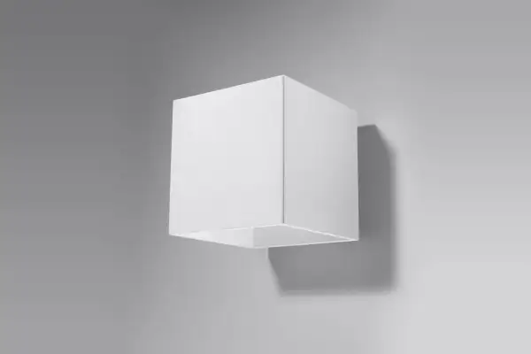 Minimalistyczna lampa kostka w kolorze białym, zamontowana na szarej ścianie. Rzuca subtelny cień.