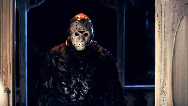 Jason Voorhees, ikonen från fredagen den 13:e filmserie-filmer, står i mörkret med sin ikoniska hockeymask.