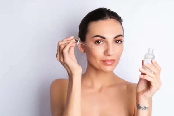 Kobieta aplikuje na twarz serum z peptydami. Skóra wygląda na nawilżoną i promienną.